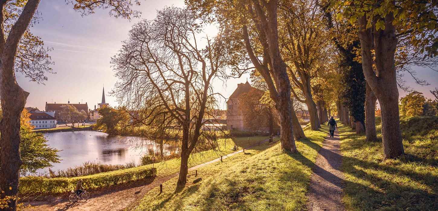 En turist går på Nyborg Vold i det flotteste efterårsvejr